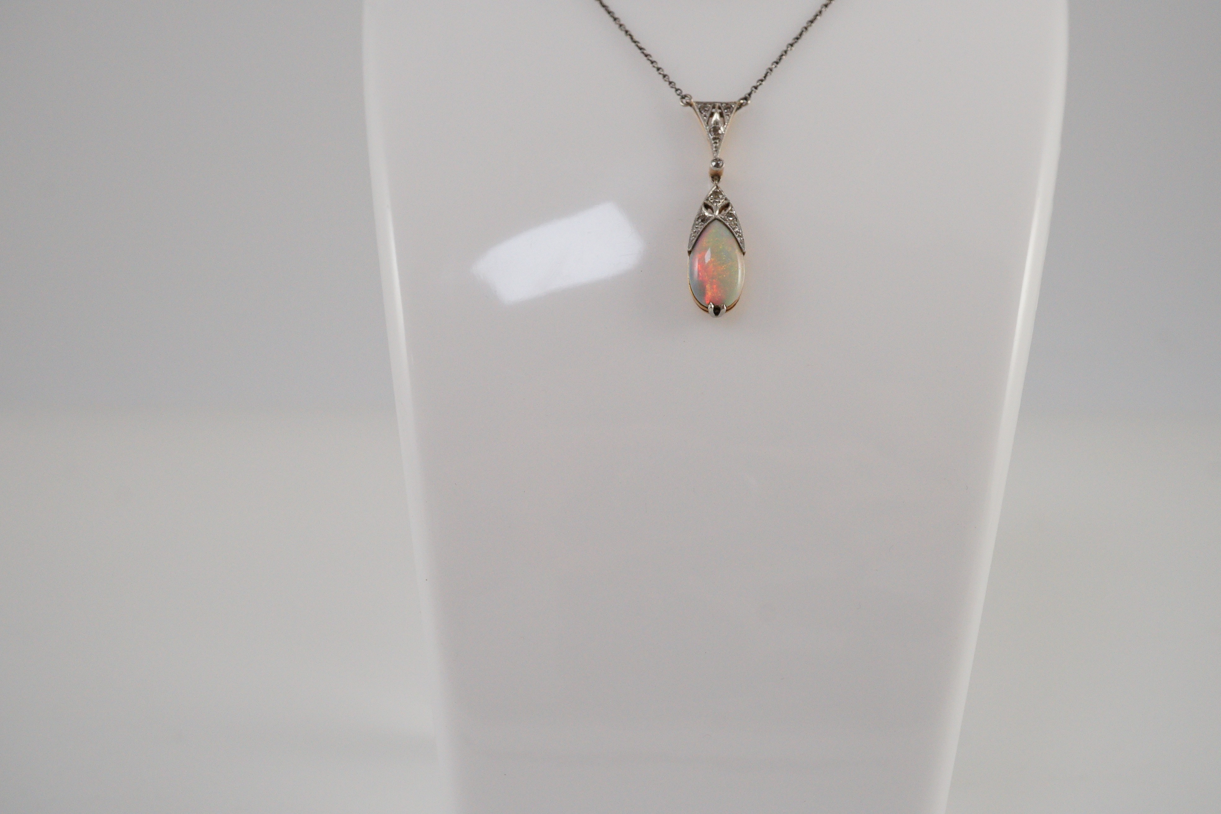 A 1920's gold and platinum, white opal and millegrain set diamond cluster pear shaped drop pendant necklace